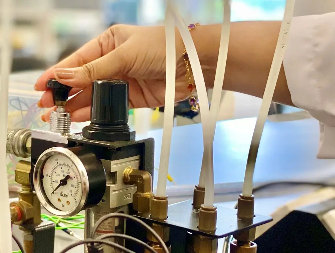 Technician adjusting an air regulator on a test rig with air tubing
